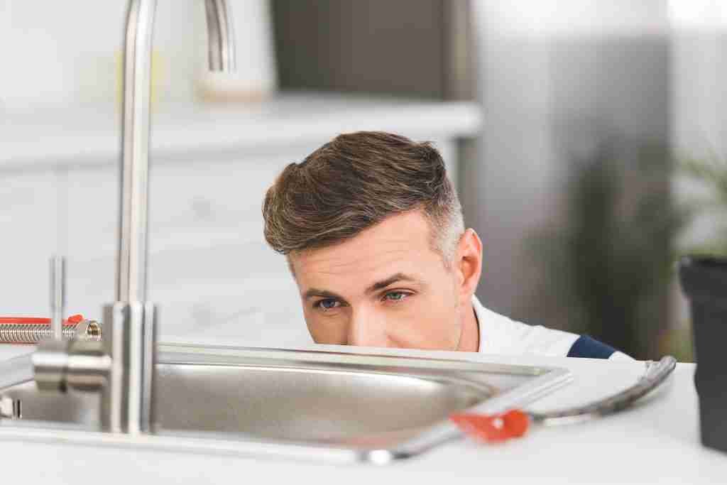 Repairman looking at sink