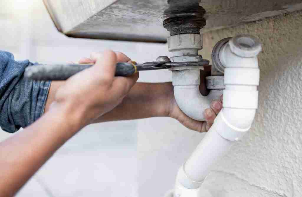 Plumber fixing a water pipe with handtool