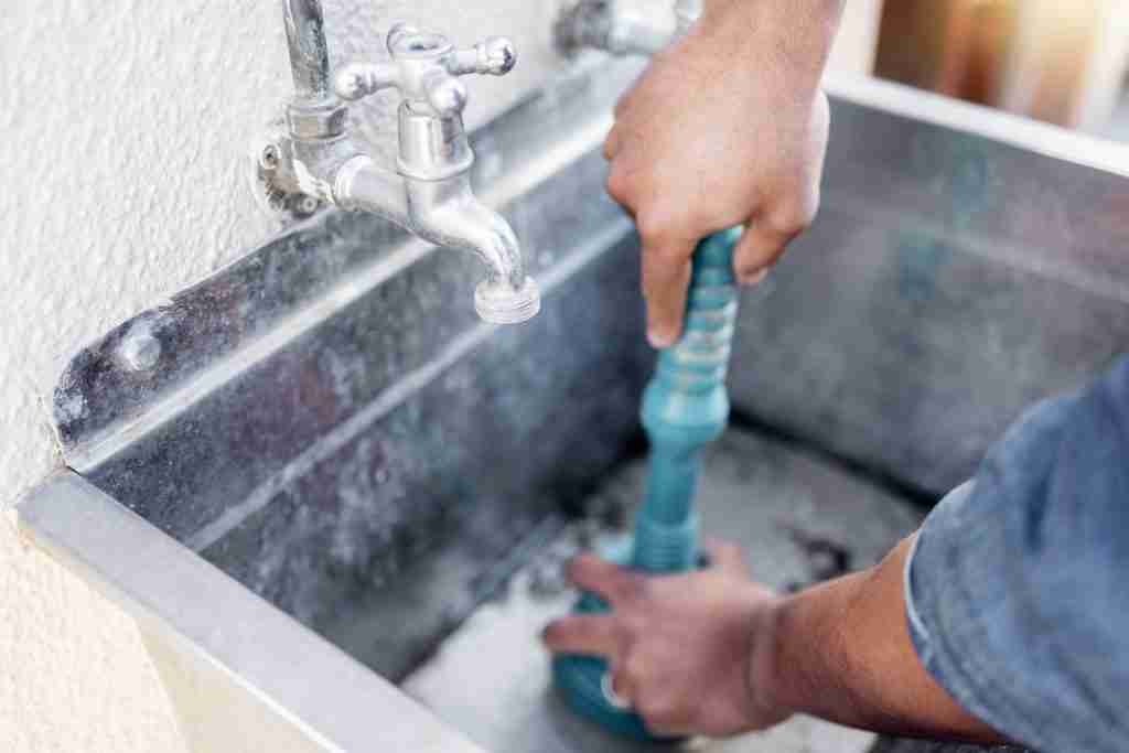 Plumber, drain and man with plunger for sink, maintenance and repairs, blockage or cleaning. Plumbi